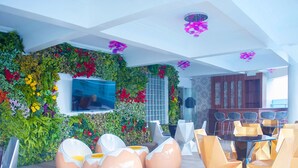 Un espacio interior moderno con pared verde, zona de estar y pantalla de televisión.