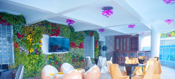 A modern indoor space with a green wall, seating area, and a TV screen.