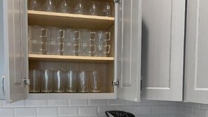 A kitchen with white cabinets, a coffee machine, and a French press. - Charming, Modern, Cozy Retreat (North Port)