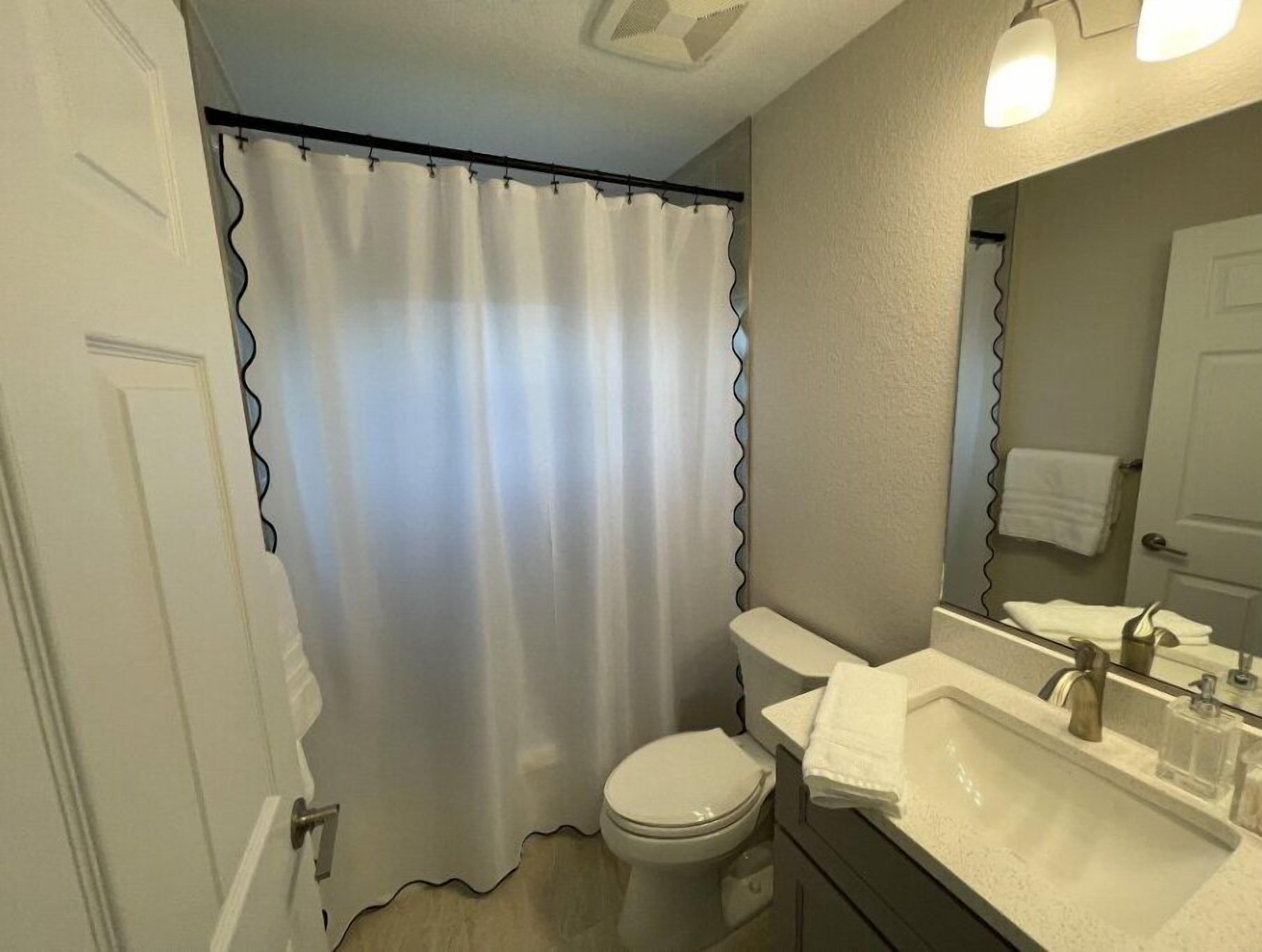 A bathroom with a toilet, sink, and shower curtain.