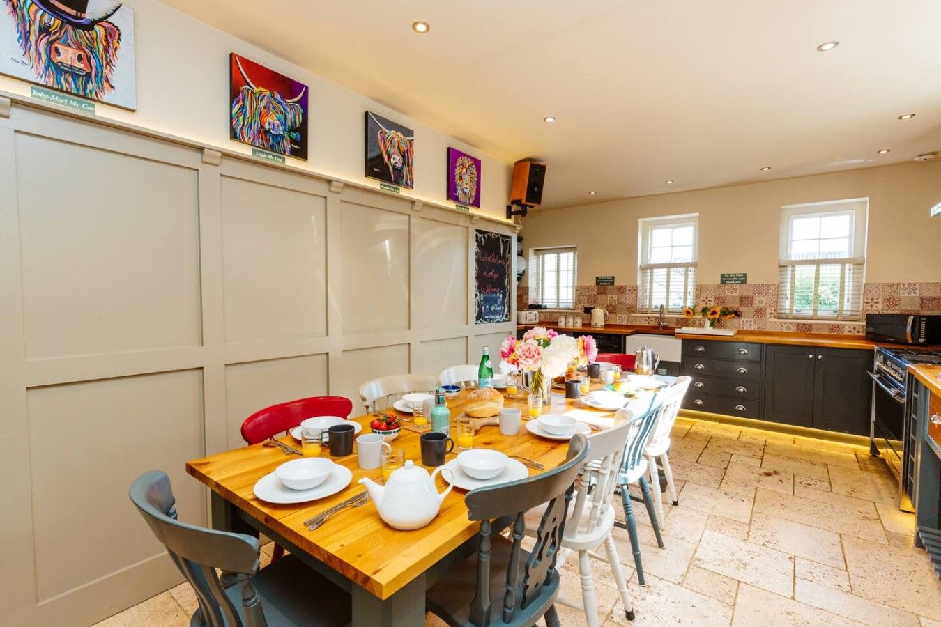 Un coin repas avec une table en bois mise pour le petit-déjeuner, entourée de chaises.