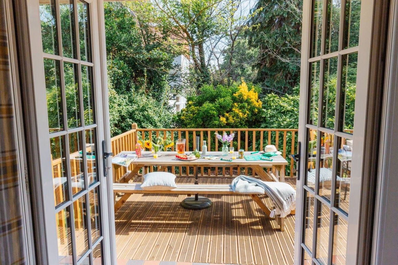 A deck with a table set for dining, surrounded by lush greenery.
