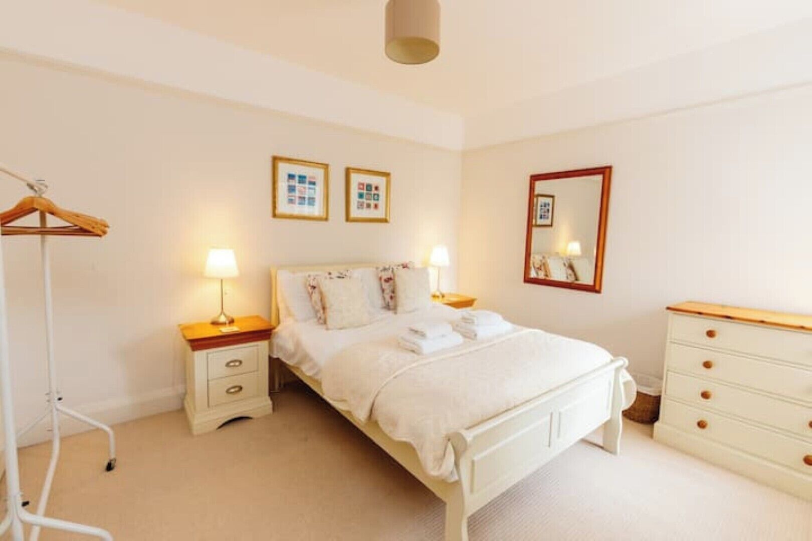 Une chambre bien rangée, avec un lit, des tables de chevet, une armoire et un miroir.