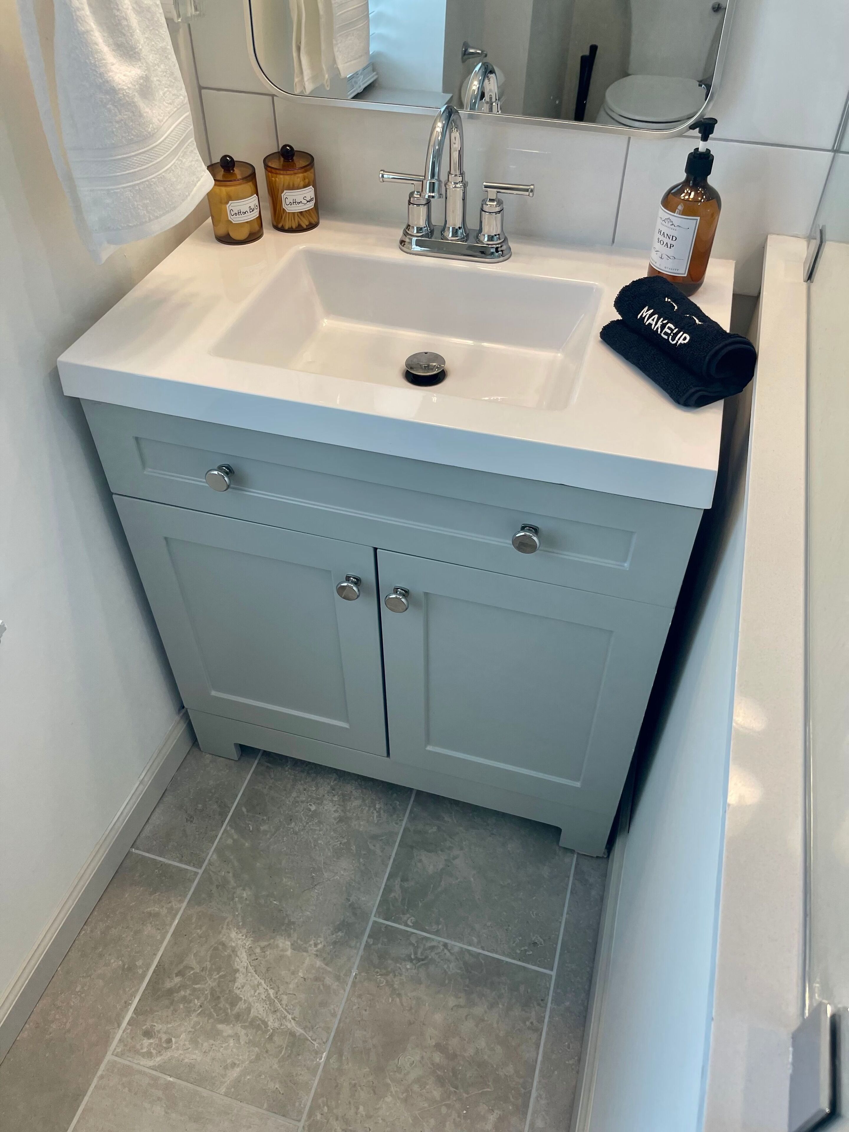 A bathroom with a white sink, two soap dispensers, and a black towel with "MAKEUP" written on it.