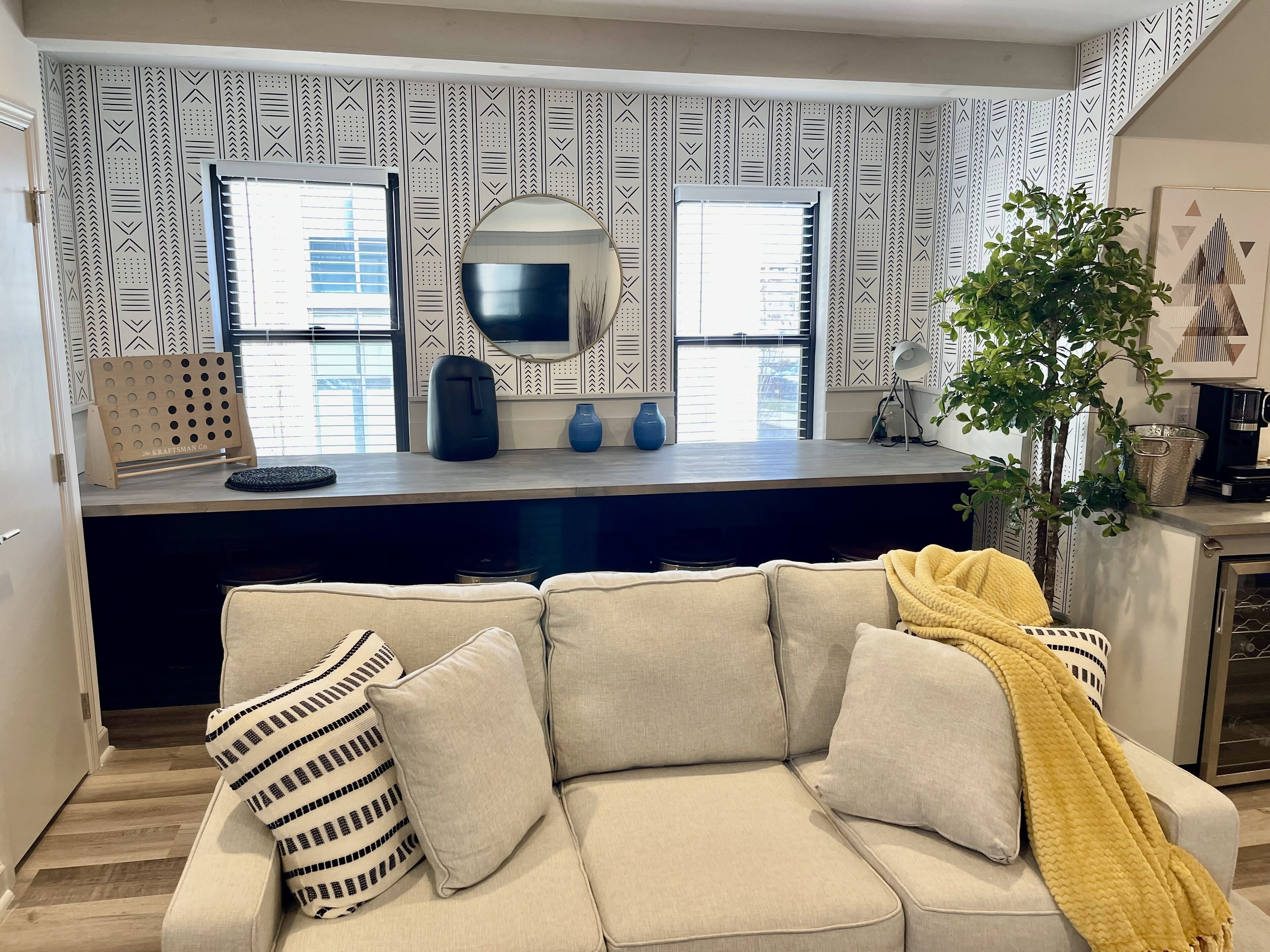 A modern kitchen with a built-in island, a large mirror, and a window with blinds.