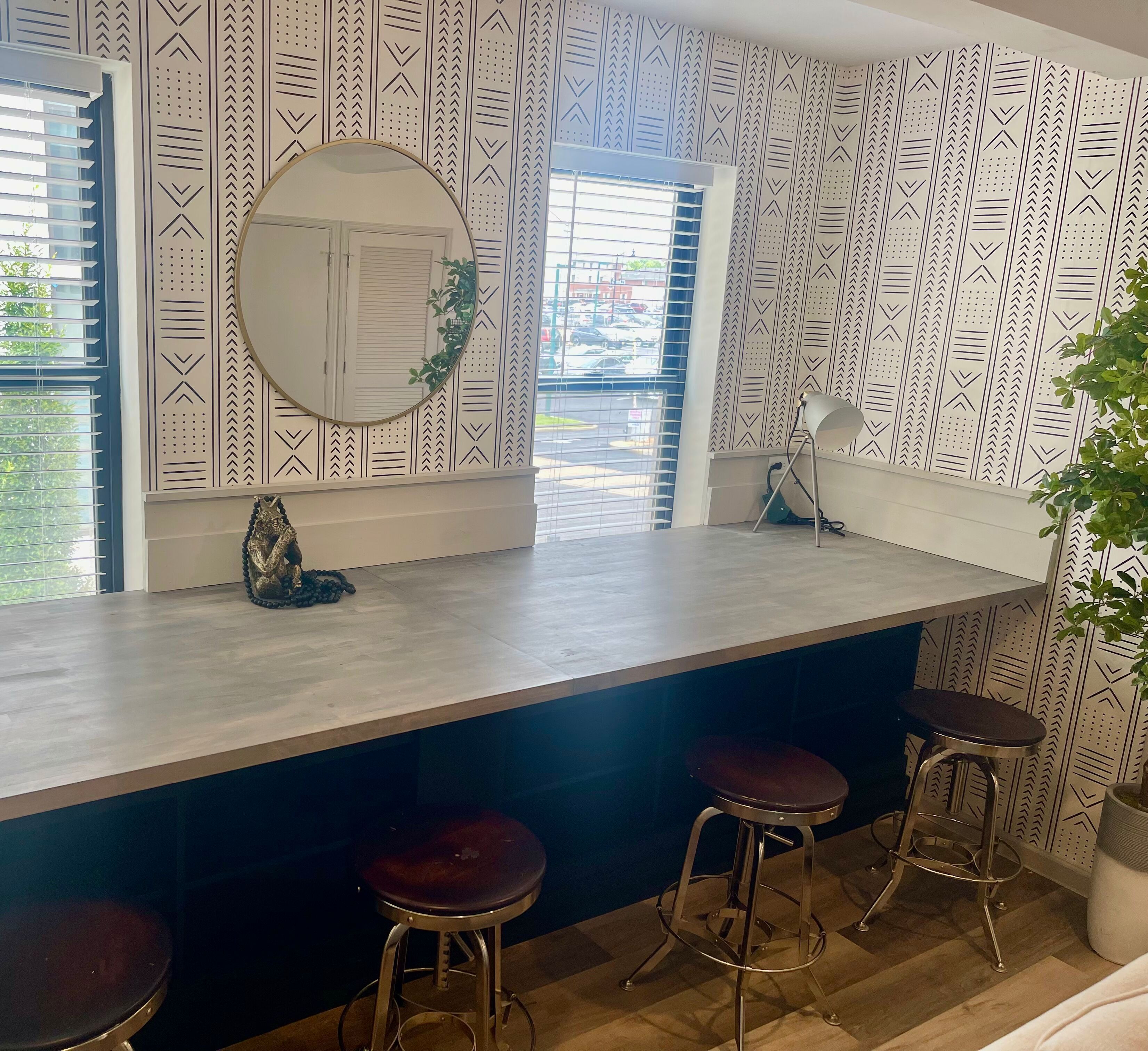 A modern kitchen with a central island, bar stools, and a large mirror.