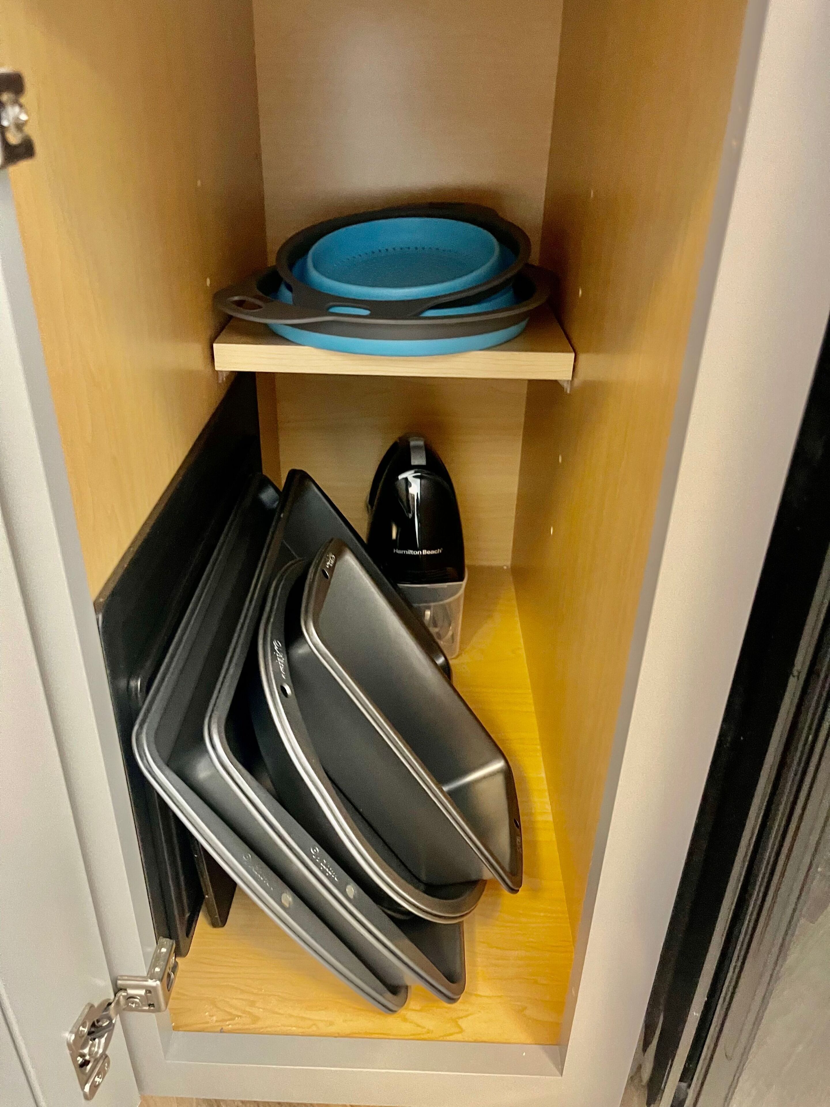 Uma cozinha compacta com uma prateleira de madeira que acomoda um prato azul e um eletrodoméstico preto.