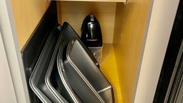 Uma cozinha compacta com uma prateleira de madeira que acomoda um prato azul e um eletrodoméstico preto.
