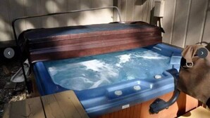 A hot tub with a wooden cover, a pump, and a control panel.