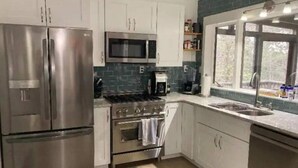 A modern kitchen with stainless steel appliances, white cabinets, and a window providing natural light.
