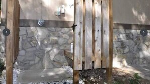 A wooden gate with a stone wall and a small window.