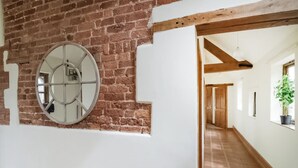 A hallway with exposed brick walls, a round mirror, and a metal rack. - 3 bedroom accommodation in Church Stretton (Church Stretton)