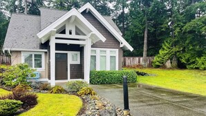 A two-story house with a front porch, a driveway, and a well-maintained lawn. - Qualicum Family Cottage - 3bd/2 bath (Qualicum Beach)