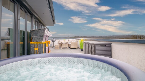 Un jacuzzi sur une terrasse sur le toit, avec des meubles d’extérieur et une vue sur le ciel.