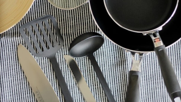 Una cucina con un piano di lavoro a righe, una padella, una spatola, un mestolo e una frusta.