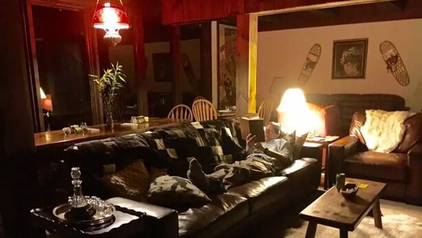 A cozy living room with a leather sofa, a coffee table, and a lamp. - Stowe Austrian Chalet (Waterbury)