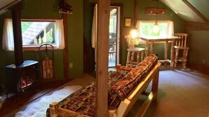 A cozy attic room with a wooden bench, a table, and a fireplace. - Green Mountain - Grunberg Haus Inn & Cabins (Waterbury)