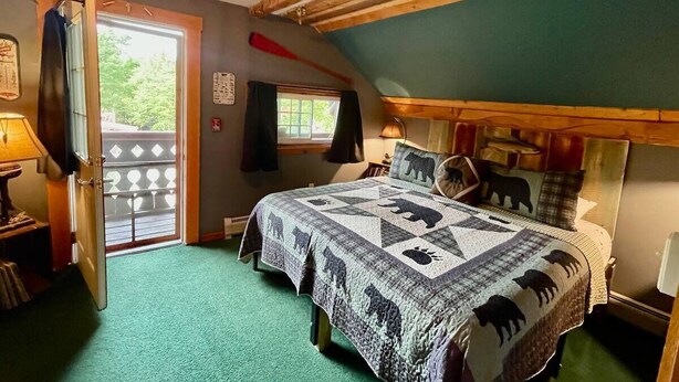Une chambre à coucher avec un lit, une fenêtre, une porte et un plafond en bois.