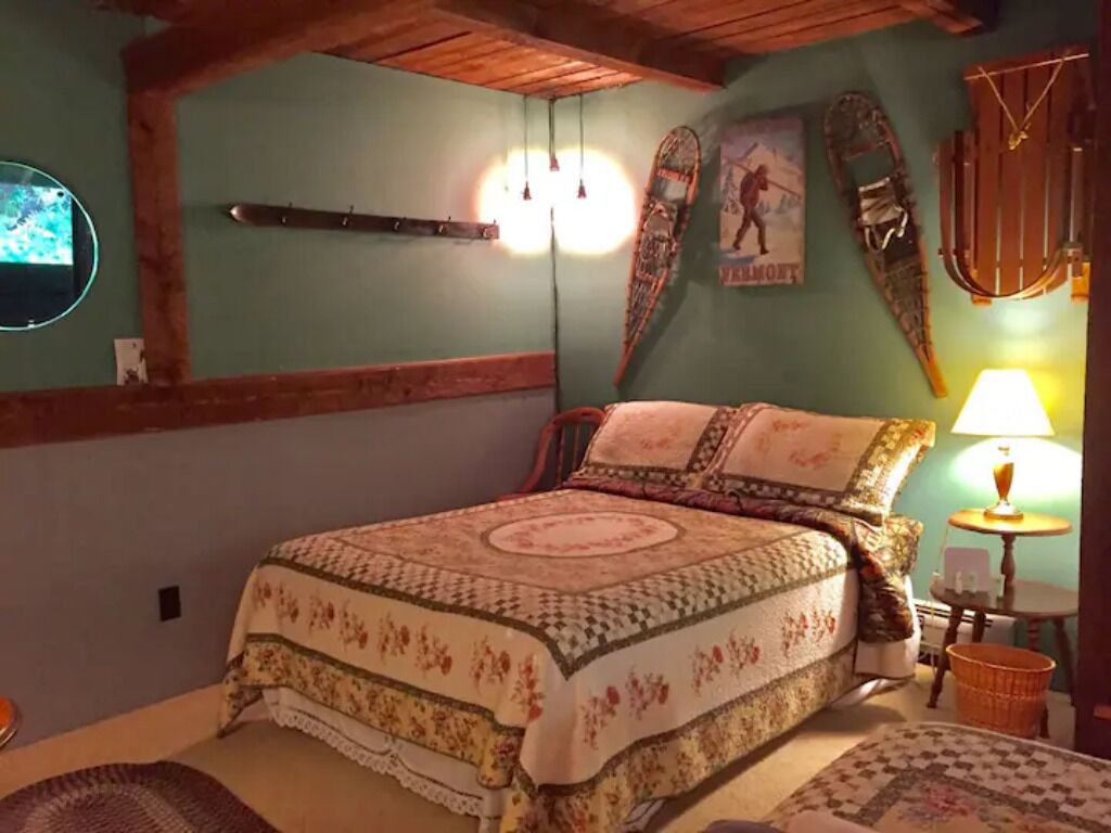 Ein gemütliches Schlafzimmer mit einem Bett, einer Holzbalkendecke, einem Wandregal und einer Lampe.