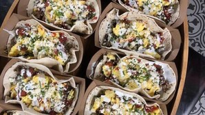 Une barquette contenant divers aliments, probablement des tacos, disposés dans une boîte en carton.