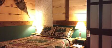 Une pièce confortable avec un lit, deux lampes de chevet, une porte en bois et un élément décoratif fixé au mur.
