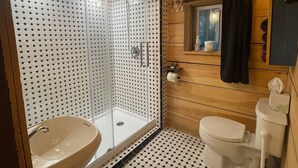 A bathroom with a glass-enclosed shower, a sink, and a toilet.