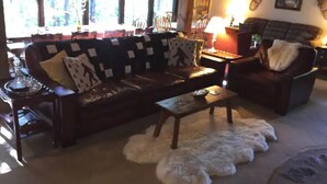 Un salon chaleureux avec un canapé aux couleurs sombres, une table basse en bois et un tapis blanc moelleux.