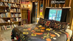Une chambre confortable avec un grand lit, une bibliothèque remplie de livres et une pancarte sur laquelle on peut lire « Spillsville ».