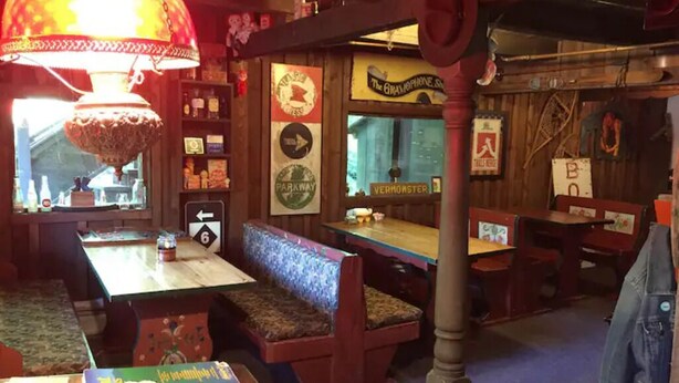 Un restaurant chaleureux, avec des meubles en bois, une lampe ancienne et divers panneaux, dont « The Gramophone Shop » et « VERMONSTER ».