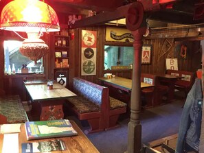 Un restaurante acogedor con muebles de madera, una lámpara vintage y varios letreros, incluyendo 'The Gramophone Shop' y 'VERMONSTER'.