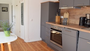 Une cuisine moderne avec des meubles gris, un plan de travail en bois et un four.