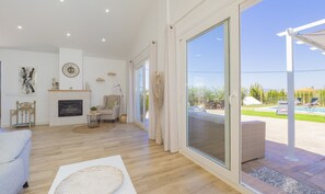 A spacious living room with a fireplace, a large sliding glass door leading to an outdoor area with a pool and lounge chairs. - Cubo's Casa Rural Huertas de Alhaurin / private pool / air conditioning / BBQ (Alhaurín el Grande)