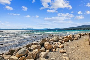 A rocky shoreline with large boulders and a clear view of the ocean and distant mountains.