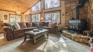 A cozy living room with a stone fireplace, large windows, and a wooden ceiling. - Beautiful Cabin In Tahoe Vista! (Tahoe Vista)