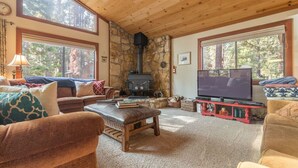 A cozy living room with a stone fireplace, large windows, and comfortable seating. - Beautiful Cabin In Tahoe Vista! (Tahoe Vista)