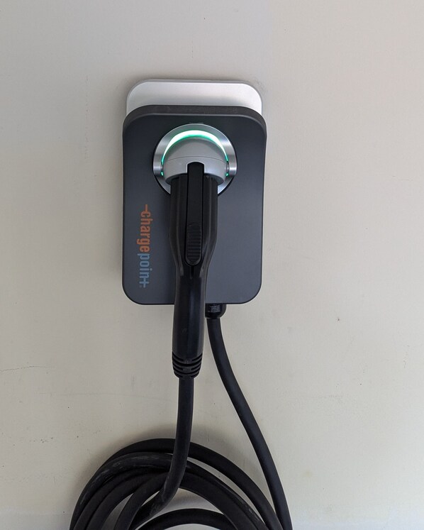 A wall-mounted charging station with a black cable plugged in.