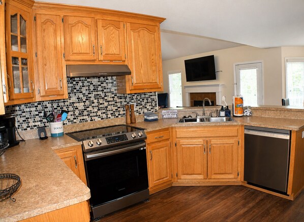 A kitchen with wooden cabinets, a black stove, a dishwasher, and a tiled backsplash.