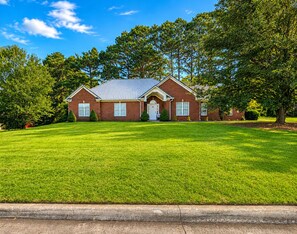 A two-story brick house with a front lawn, a garage, and a driveway.