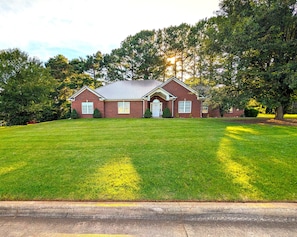 A two-story brick house with a front lawn, a garage, and a driveway.