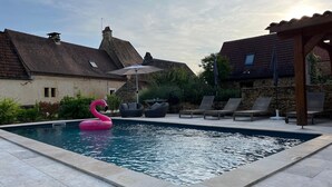 A swimming pool with a pink flamingo float, lounge chairs, and a pergola. - Piscine, Charme & Calme au Coeur du Périgord Noir (Castels et Bézenac)