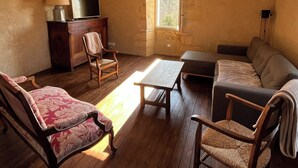 A cozy living room with wooden flooring, a sofa, a coffee table, and two chairs. - Piscine, Charme & Calme au Coeur du Périgord Noir (Castels et Bézenac)