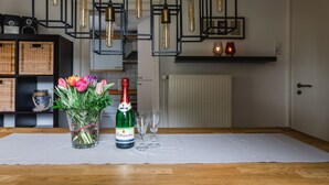A table with a bottle of champagne, two glasses, and a vase of tulips. - Ferienhaus in Ortsrandlage mit Aussensauna und Beleuchteter Glasüberdachung (Eslohe (Sauerland))