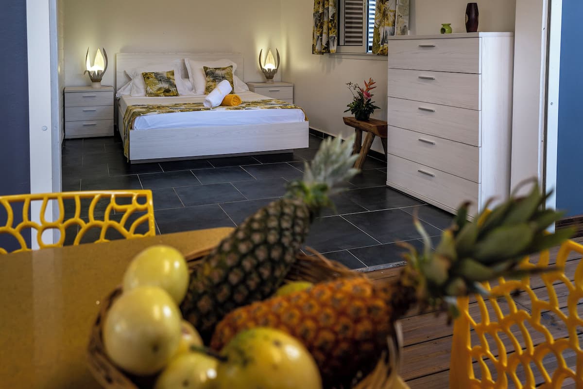 A hotel room with a bed, bedside tables, a dresser, and a dining area with a table and chairs.