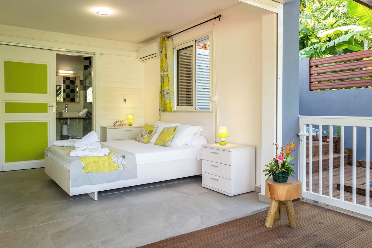 A bedroom with a bed, bedside table, and a small wooden stool with a plant.
