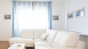 A modern living room with a white sectional sofa, a wooden coffee table, and two framed pictures on the wall.