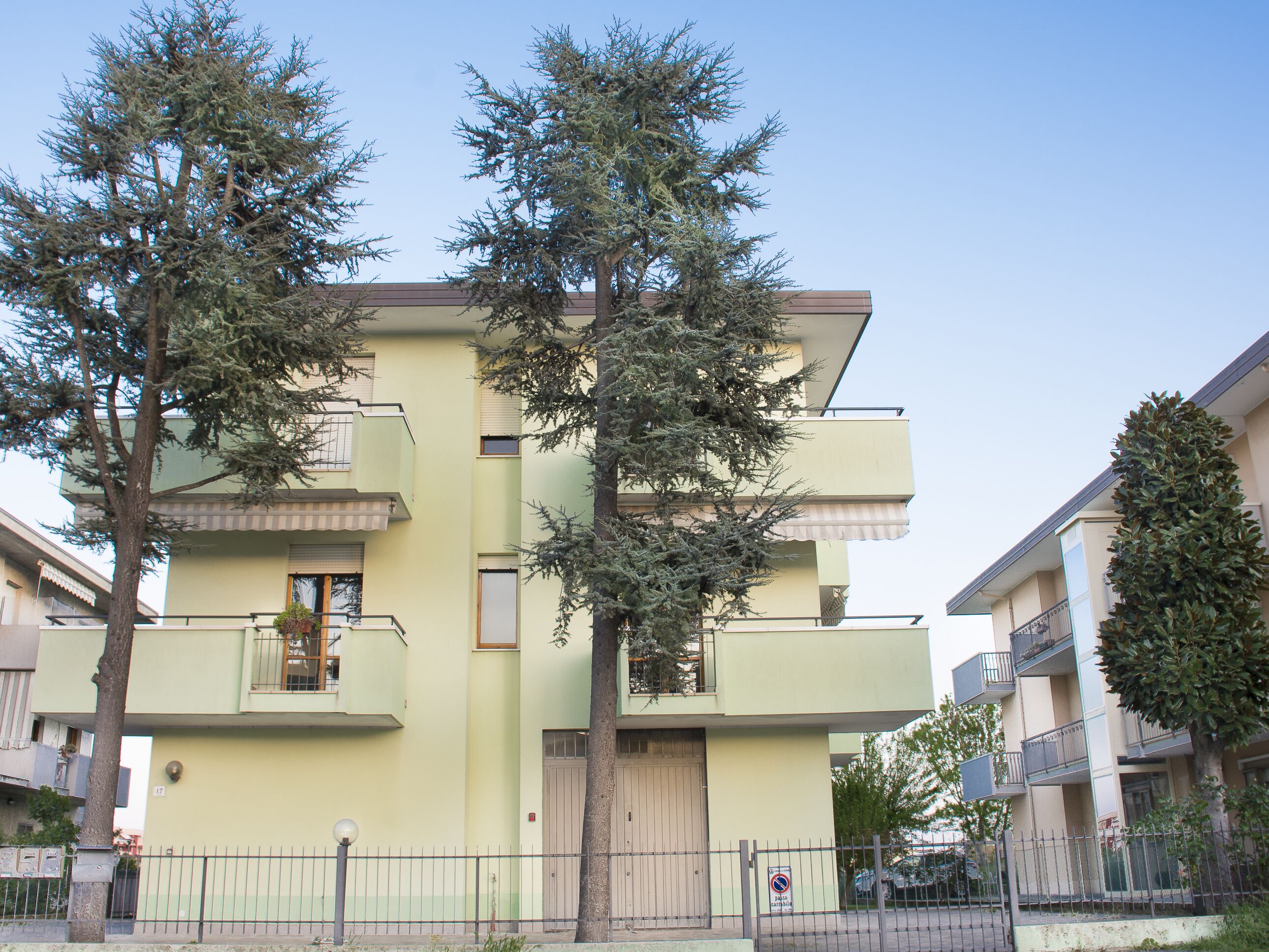 A multi-story building with balconies and a gated entrance.