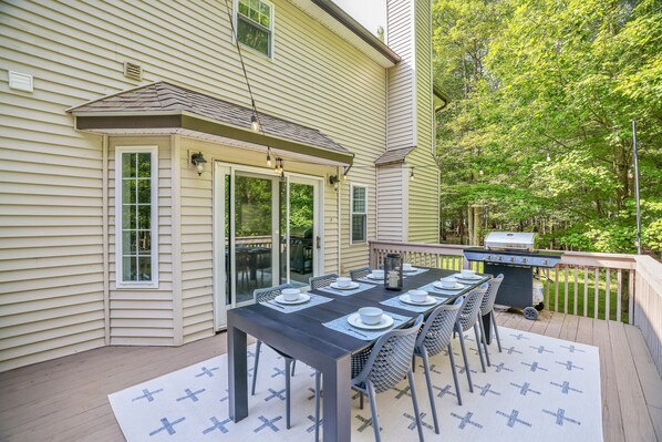 Een terras met een eettafel voor zes personen, een barbecue en een overdekt patio.