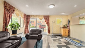 A hotel lobby with a checkered floor, leather sofas, a coffee table, and a reception desk. - The Cayuga Inn at the Finger Lakes (Auburn)