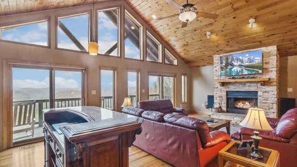 A spacious living room with a fireplace, large windows, and a wooden ceiling. - Lovely Cabin on Appalachian Ski Mountain (Blowing Rock)