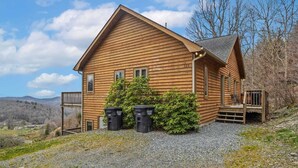 A wooden cabin with a porch, a gravel driveway, and a view of the surrounding landscape. - Lovely Cabin on Appalachian Ski Mountain (Blowing Rock)